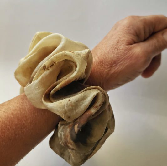 Gros plan d'un chouchou volumineux en soie naturelle porté au poignet pour montrer la texture et le brillant du tissu.