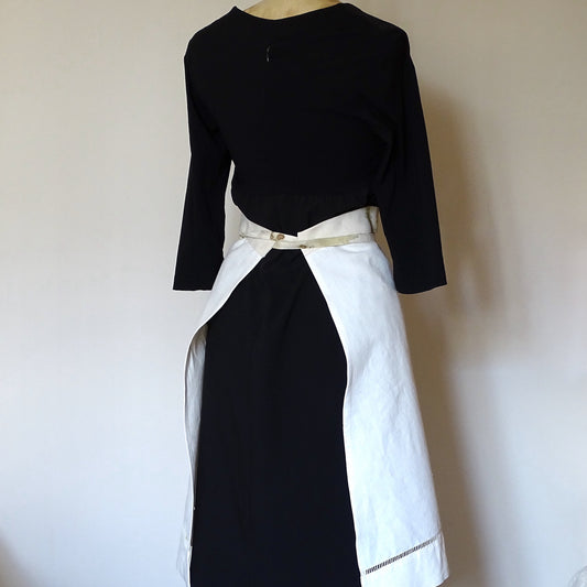 Vue arrière d'un demi-tablier en lin blanc montrant le nouage de la ceinture imprimée aux végétaux.